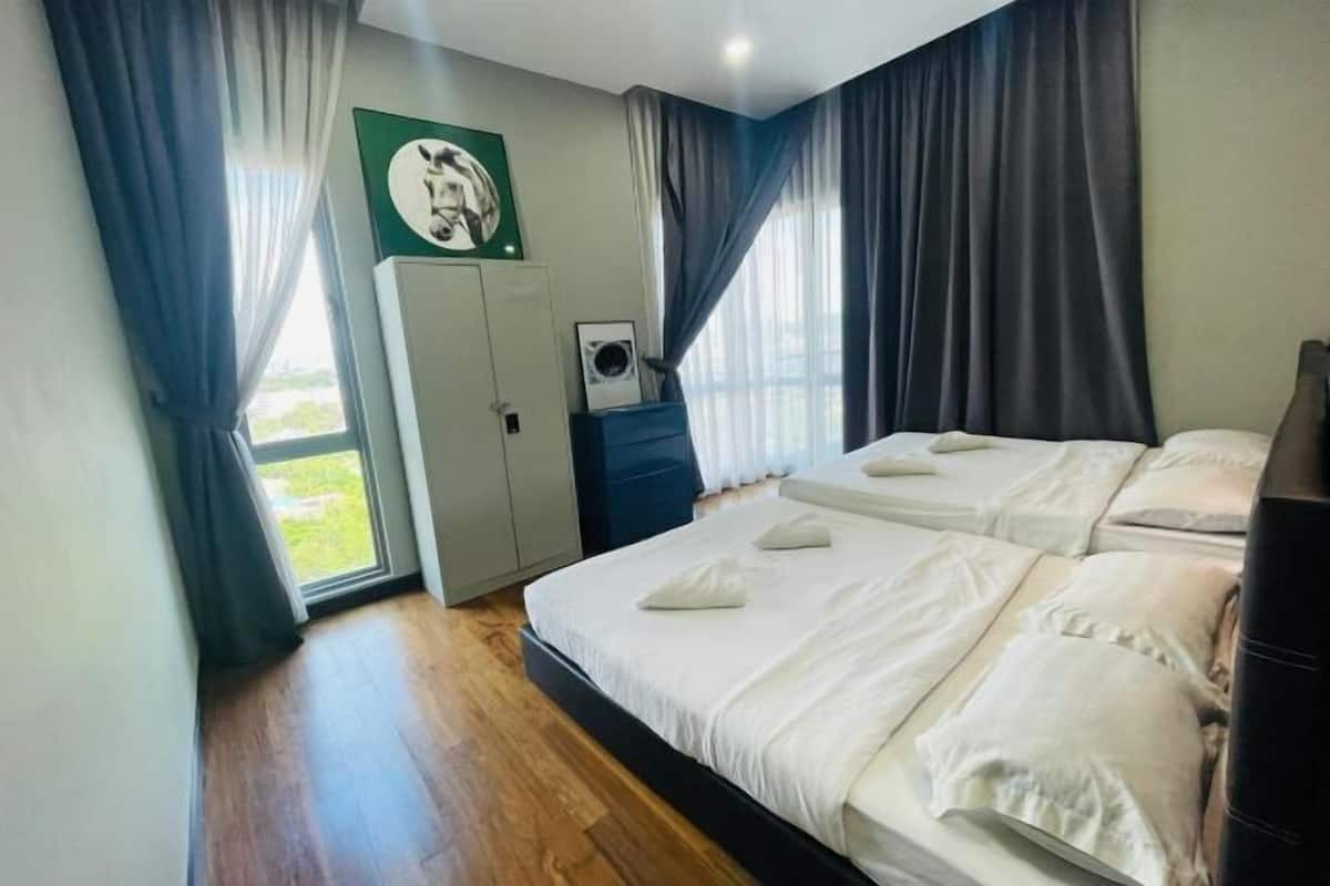 A hotel room with two beds, a wardrobe, a small table, and a window with curtains.