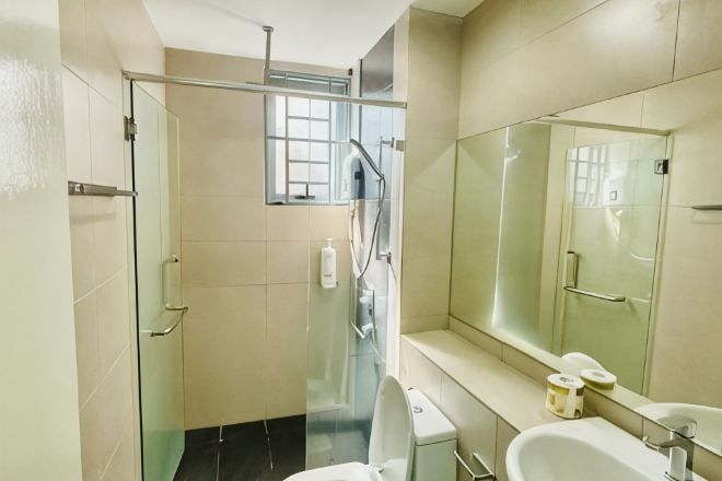 A modern bathroom with a glass shower enclosure, a toilet, a sink, and a large mirror.