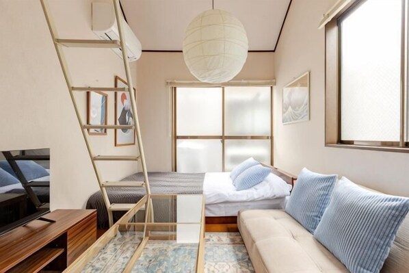 Une chambre moderne avec un canapé, un lit, une échelle et une grande fenêtre.