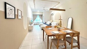 A modern dining area with a wooden table, wicker chairs, and a long view into the living room. - Akademik Suite, Moccasin Suite by Antlerzone (Tebrau)