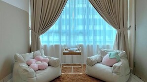 A room with two white armchairs, a small table with a book, and a window with sheer curtains. - Akademik Suite, Moccasin Suite by Antlerzone (Tebrau)