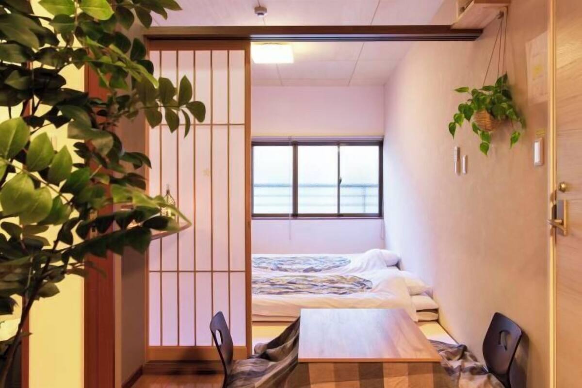 Une chambre de taille modeste, avec un lit, une petite table et une vue sur la mer par la fenêtre.