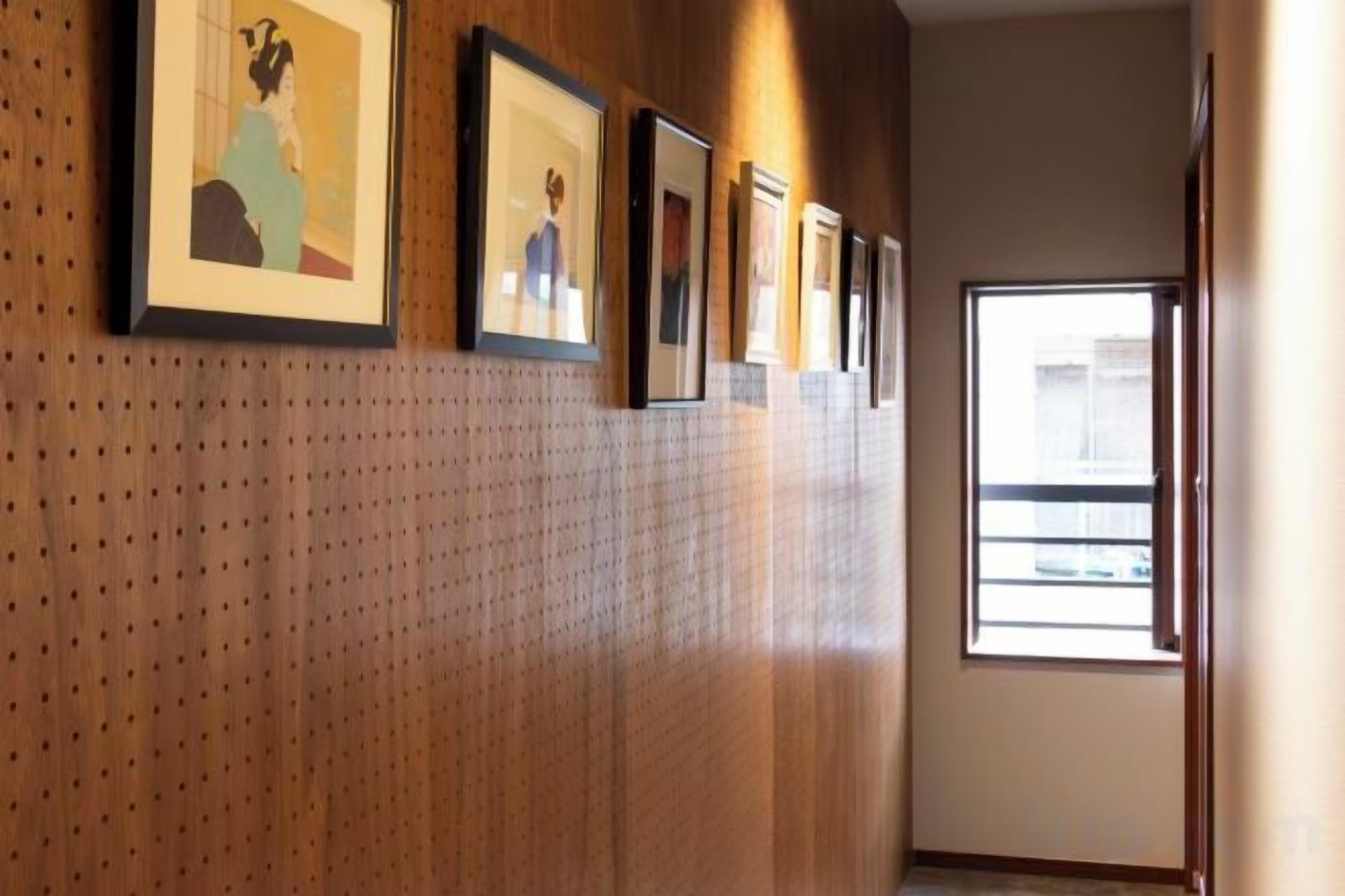A hallway with framed artwork on the wall, a window with a view, and a door on the right.