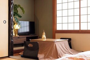A room with a bed, a television, a table with a lamp, and a window. - Lumie （Tamatsukuri） (Osaka)