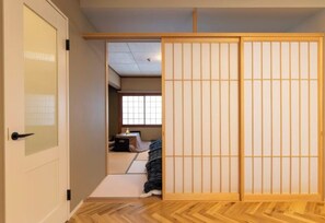 A traditional Japanese room with tatami flooring, a sliding shoji screen door, and a low wooden bed. - Lumie (Tamatsukuri) (Osaka)
