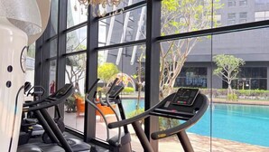 Un gimnasio con cintas de correr y un amplio ventanal con vistas a una piscina y zona exterior.
