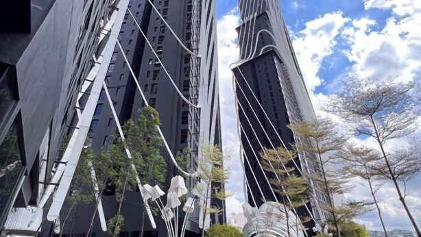 Un edificio moderno de rascacielos con un diseño arquitectónico único, caracterizado por múltiples líneas verticales y una combinación de superficies oscuras y claras.