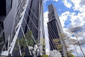 Een modern hoog gebouw met een uniek architectonisch ontwerp, gekenmerkt door meerdere verticale lijnen en een combinatie van donkere en lichte oppervlakken.