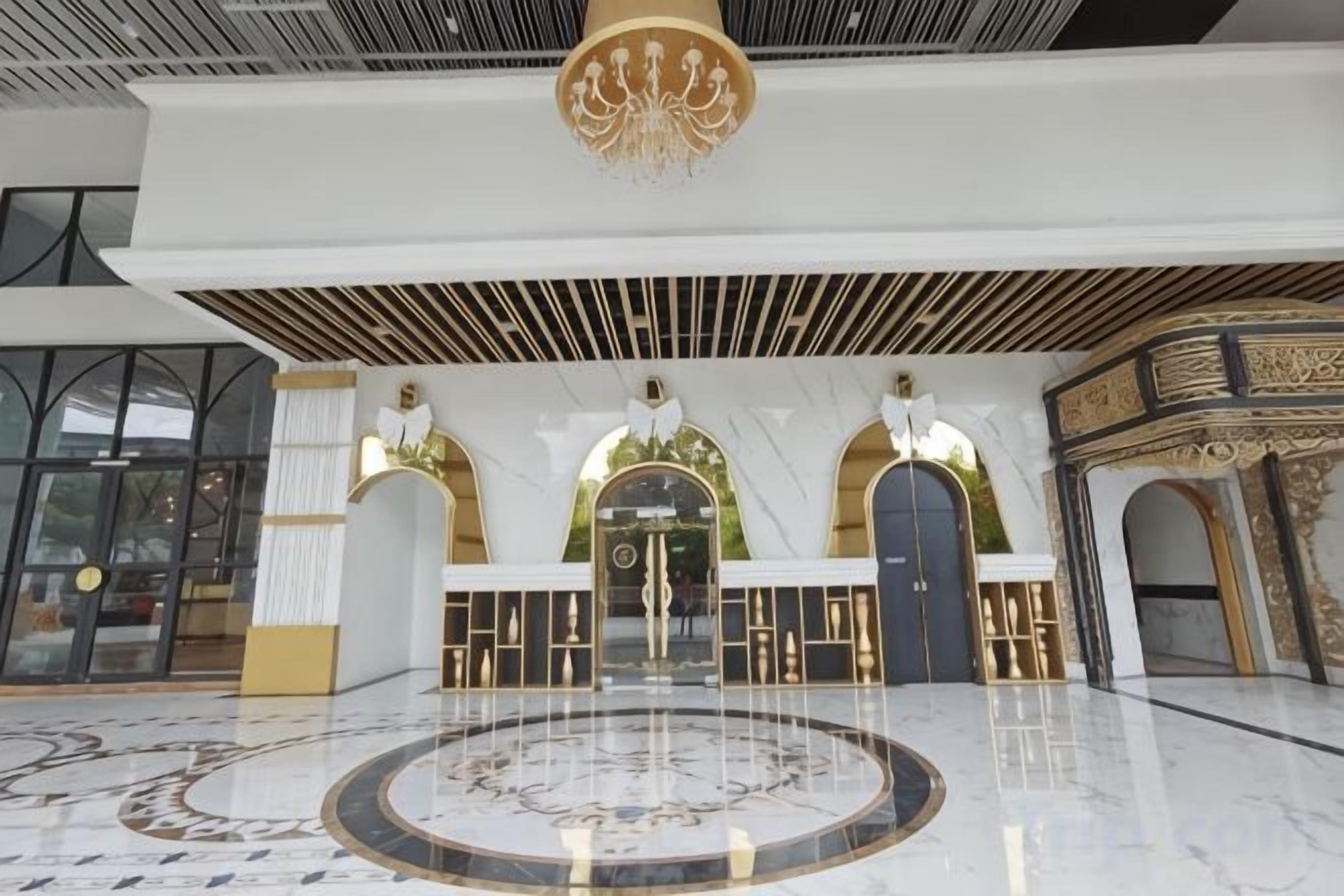 A spacious lobby with a marble floor, a central fountain, and ornate architectural details.