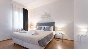 Une chambre d’hôtel moderne avec un grand lit, des tables de chevet avec des lampes et un élément décoratif mural.