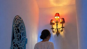 Une personne descend un escalier en marbre dans un bâtiment doté d’une porte en métal décorative et d’un éclairage mural.