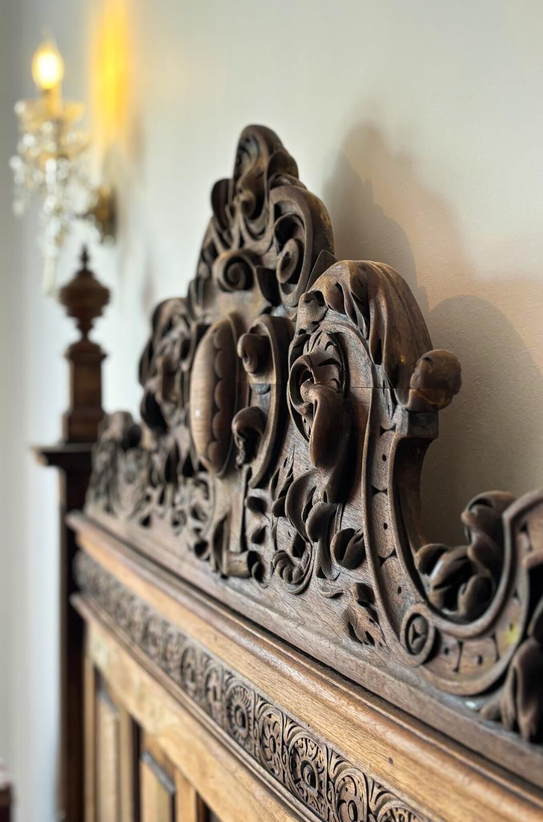 Una testiera in legno finemente intagliata, con motivi floreali e animali intricati.
