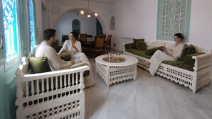 Une pièce meublée de blanc, avec un coin repas et des éléments décoratifs.