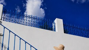 Une personne descend un escalier en métal bleu, avec des murs blancs et une clôture en métal bleu en arrière-plan.