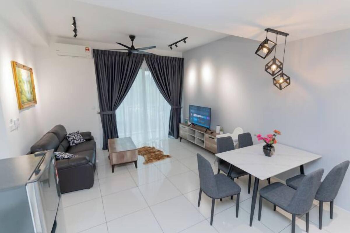A modern living room with a sofa, dining table, chairs, a TV, and a ceiling fan.