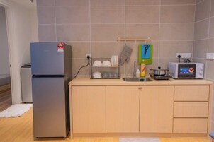 A kitchen with a refrigerator, microwave, and a sink.