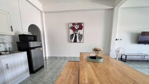 Eine moderne Küche mit weißen Schränken, einem schwarzen Kühlschrank und einem Holztisch mit Blumen in einer Vase.