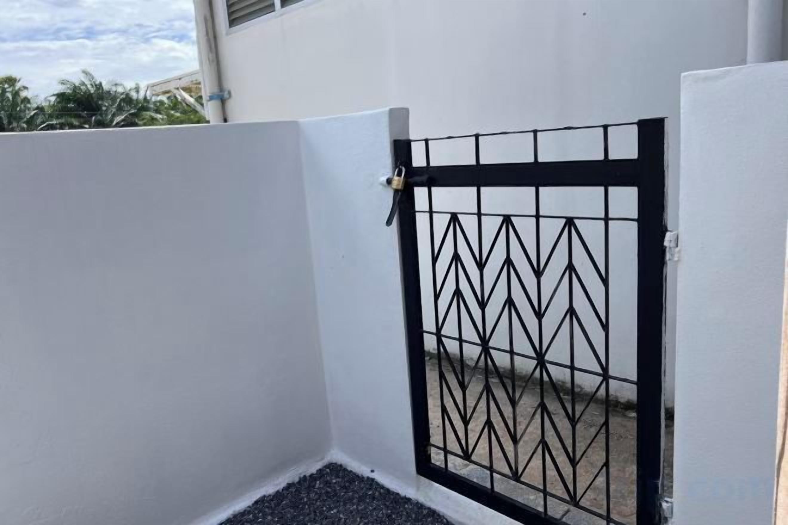 A gated area with a metal gate and a white wall.