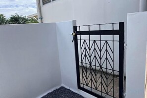 A gated area with a metal gate and a white wall. - Kuan Mapraw Villa 2 (Phatthalung)
