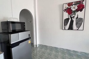 A kitchenette with a microwave and a coffee maker, a framed artwork on the wall, and a tiled floor. - Kuan Mapraw Villa 2 (Phatthalung)