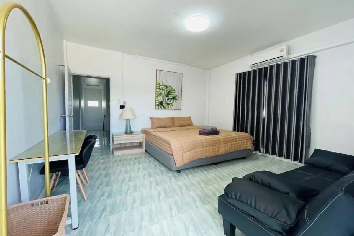 Une chambre à coucher comprenant un lit, un bureau, une chaise, un canapé, une lampe et un radiateur.