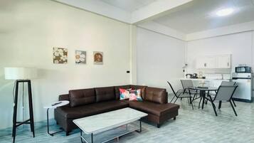 Una sala de estar con un sofá seccional marrón, una mesa de centro y un comedor con una mesa y sillas.