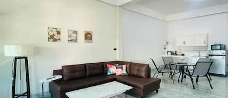 Una sala de estar con un sofá seccional marrón, una mesa de centro y un comedor con una mesa y sillas.