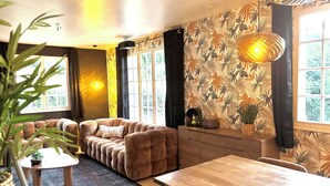 A modern living room with a sofa, a wooden dining table, and a patterned wallpaper. - Villa Hakuna Matata heated pool 4 bedrooms near Périgueux in a quiet location (Château-l'Évêque)