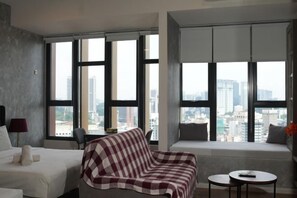Et moderne hotelværelse med et stort vindue, en seng, en sofa, et lille bord og en stol.
