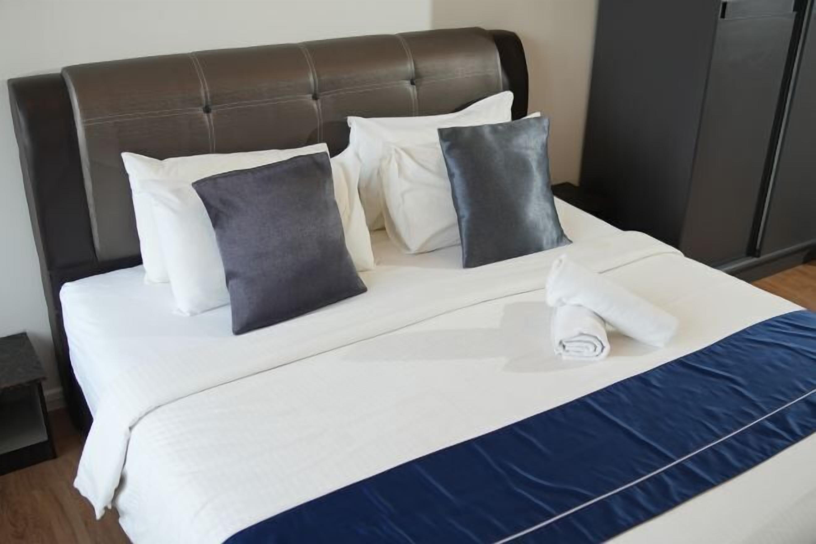A bed with a headboard, pillows, and a rolled towel.