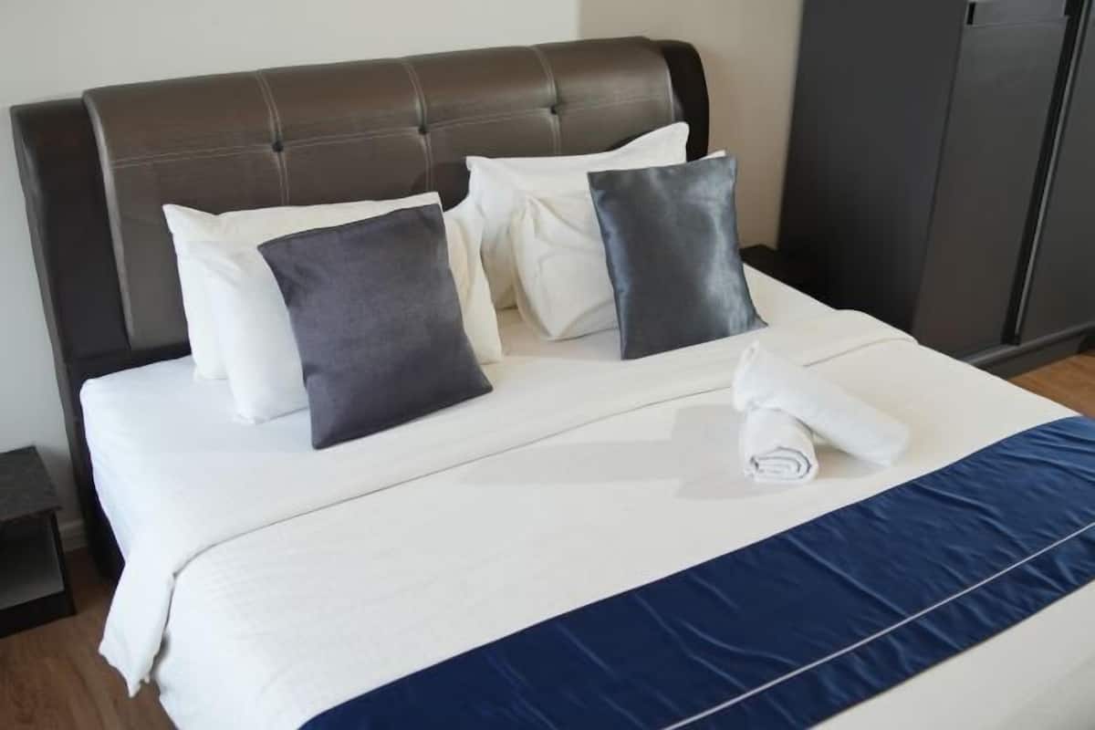 A bed with a headboard, pillows, and a rolled towel.