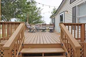 A wooden deck with a set of outdoor furniture and a staircase leading to a house. - The Hill House at Quail Creek Ranch (Wheeler)