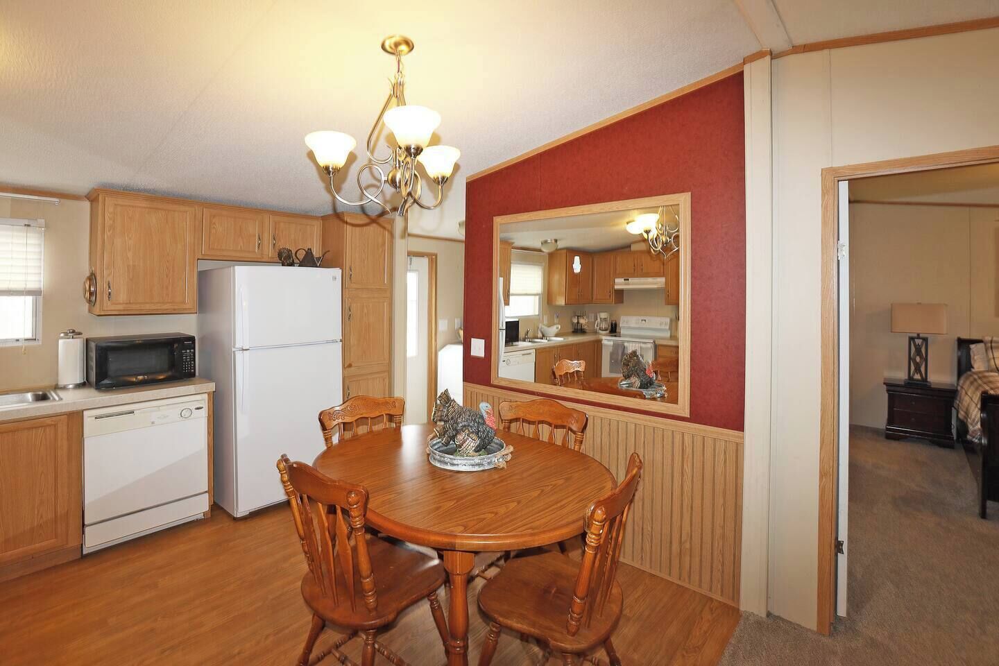 A compact kitchen with wooden cabinets, a white refrigerator, a microwave, and a dining table with chairs.