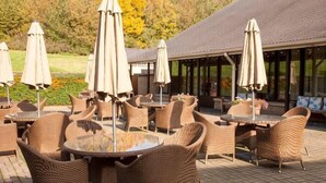 Outdoor wicker furniture, umbrellas, and a building with a tiled roof. - Holiday Inn LEEDS - BRIGHOUSE by IHG (Brighouse)