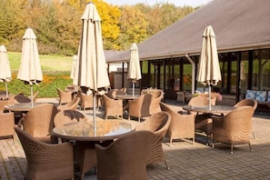 Outdoor wicker furniture, umbrellas, and a building with a tiled roof. - Holiday Inn LEEDS - BRIGHOUSE by IHG (Brighouse)