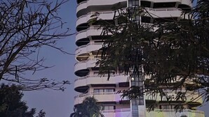 A multi-story hotel with a central staircase, surrounded by palm trees and a well-lit entrance area. - VIP Condominium GoldenEye - Hua Hin/Cha-am - TOP VIEW on beach/city/mountains (Tambon Cha-am)