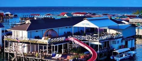 Un hotel flotante con un tobogán rojo, varios niveles y vistas al océano.