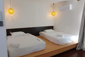 A hotel room with two single beds, a wooden platform, white bedding, and two hanging spherical light fixtures. - Aloha MABUL Scuba Lodge (Semporna)