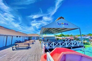 A wooden deck with lounge chairs and a covered seating area with a sign reading 'LHA'. - Aloha MABUL Scuba Lodge (Semporna)