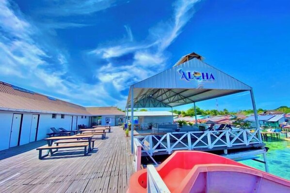 Un muelle de madera con sillas de descanso y una zona de estar cubierta con un letrero que dice 'LHA'.