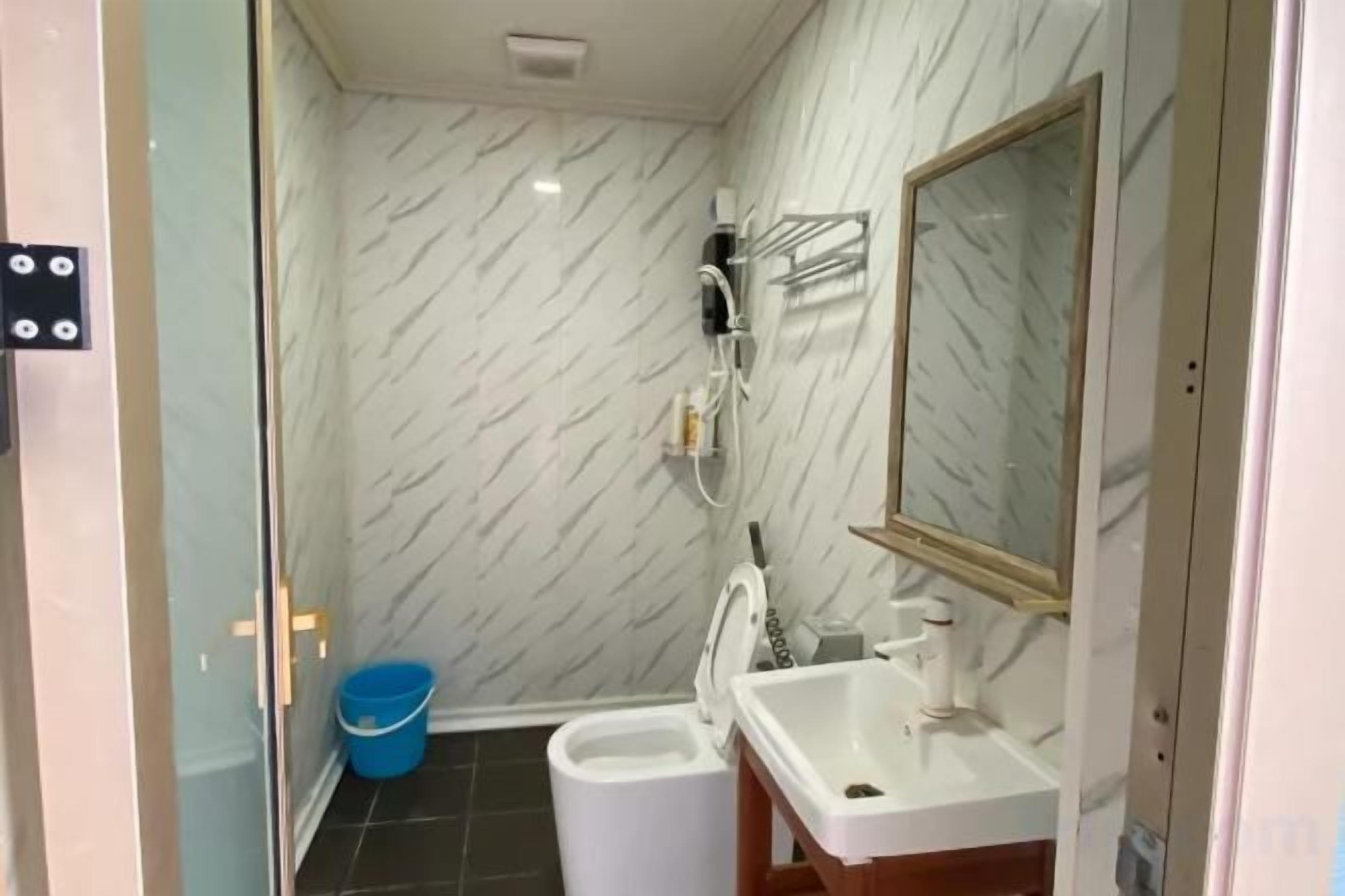 A bathroom with a shower, toilet, sink, and a mirror.