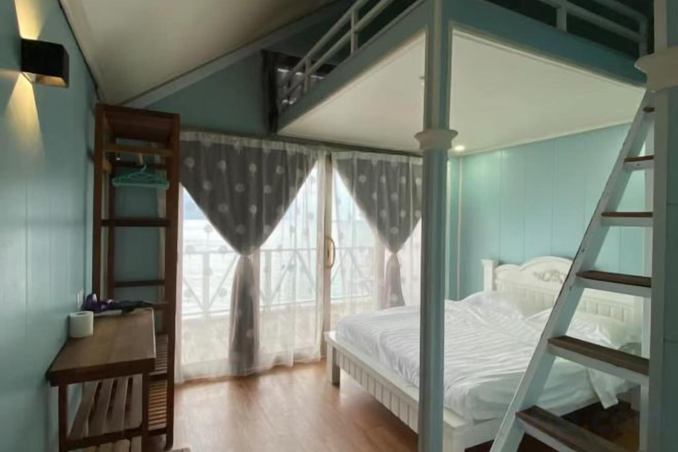 Un dormitorio con literas, un escritorio con silla y una escalera.