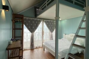 Ein Schlafzimmer mit einem Etagenbett, einem Schreibtisch mit Stuhl und einer Leiter.