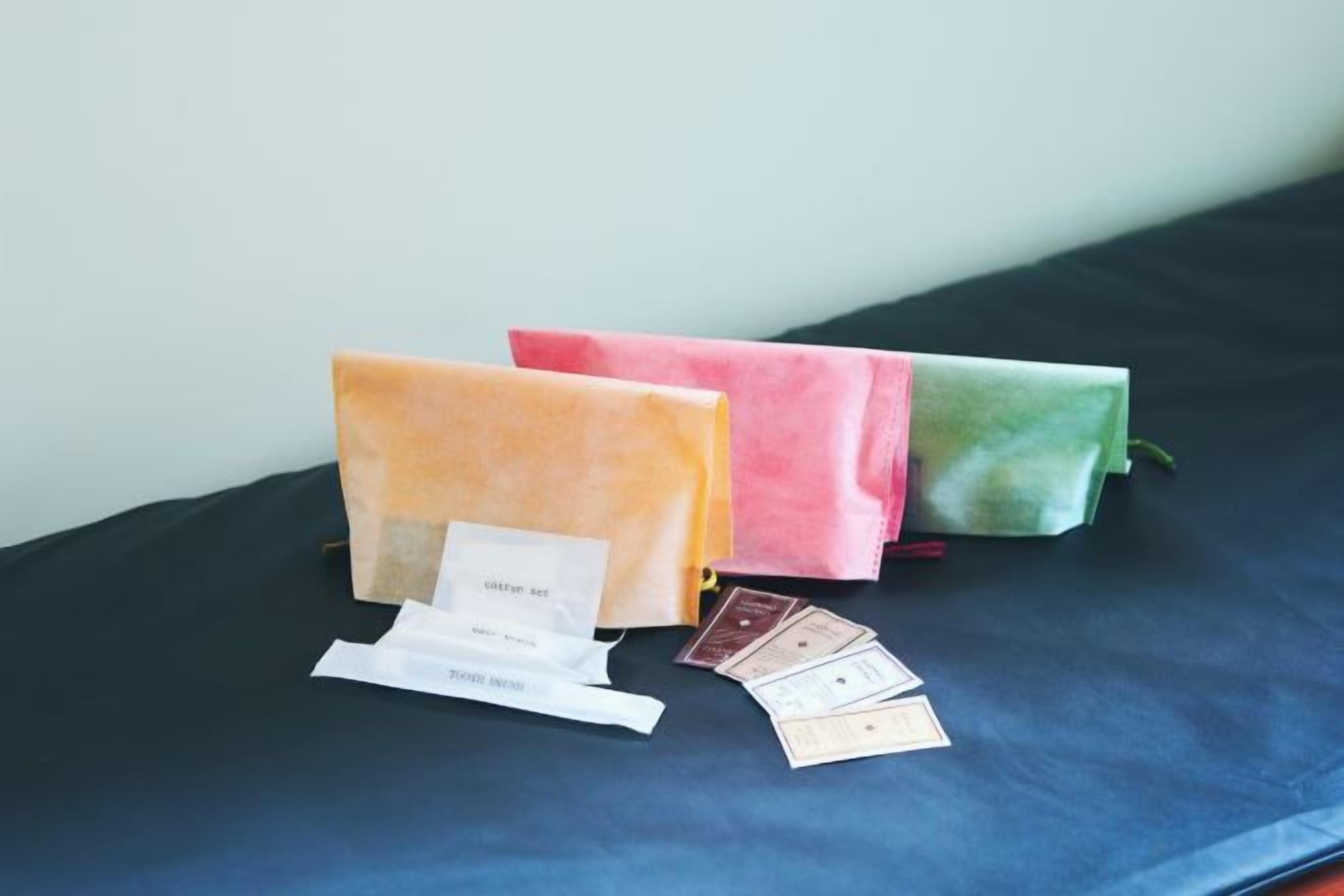 Three fabric bags on a dark surface with a white tag and a few cards.