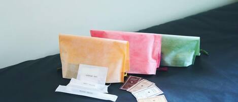 Three fabric bags on a dark surface with a white tag and a few cards.