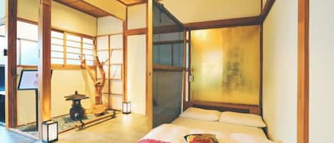 A traditional Japanese room with tatami flooring, a low wooden bed, and sliding doors.