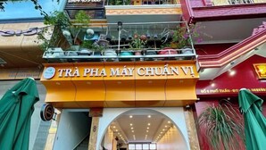 L’entrée d’un restaurant avec une enseigne indiquant : « TRÀ PHA MÁY CHUÂN VI ».