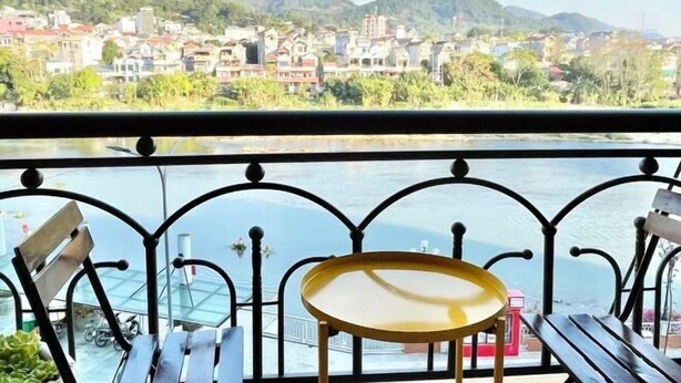 Un balcon avec une balustrade en métal, une petite table ronde et un banc.