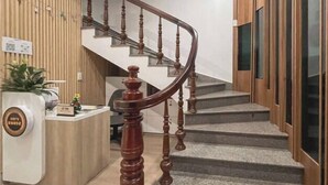 Un comptoir d’accueil avec un revêtement en bois, un escalier avec des balustrades en bois et un espace d’accueil agrémenté d’une plante et d’un petit objet décoratif.