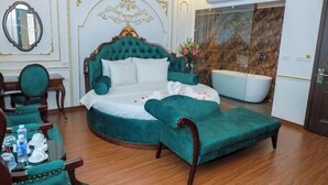 Een luxueuze slaapkamer met een groot bed, een zithoek met stoelen, een ronde tafel en een ligbad.